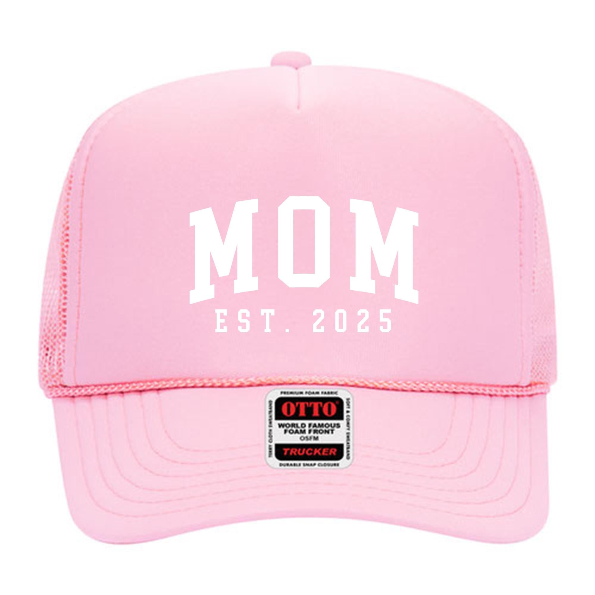 A pink trucker hat with the text &quot;MOM EST. 2025&quot; printed on it.