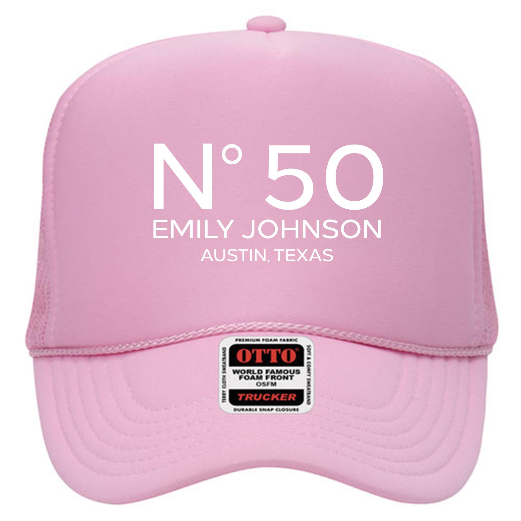 A pink trucker hat with the text &quot;N°50 EMILY JOHNSON AUSTIN, TEXAS&quot; printed on it.
