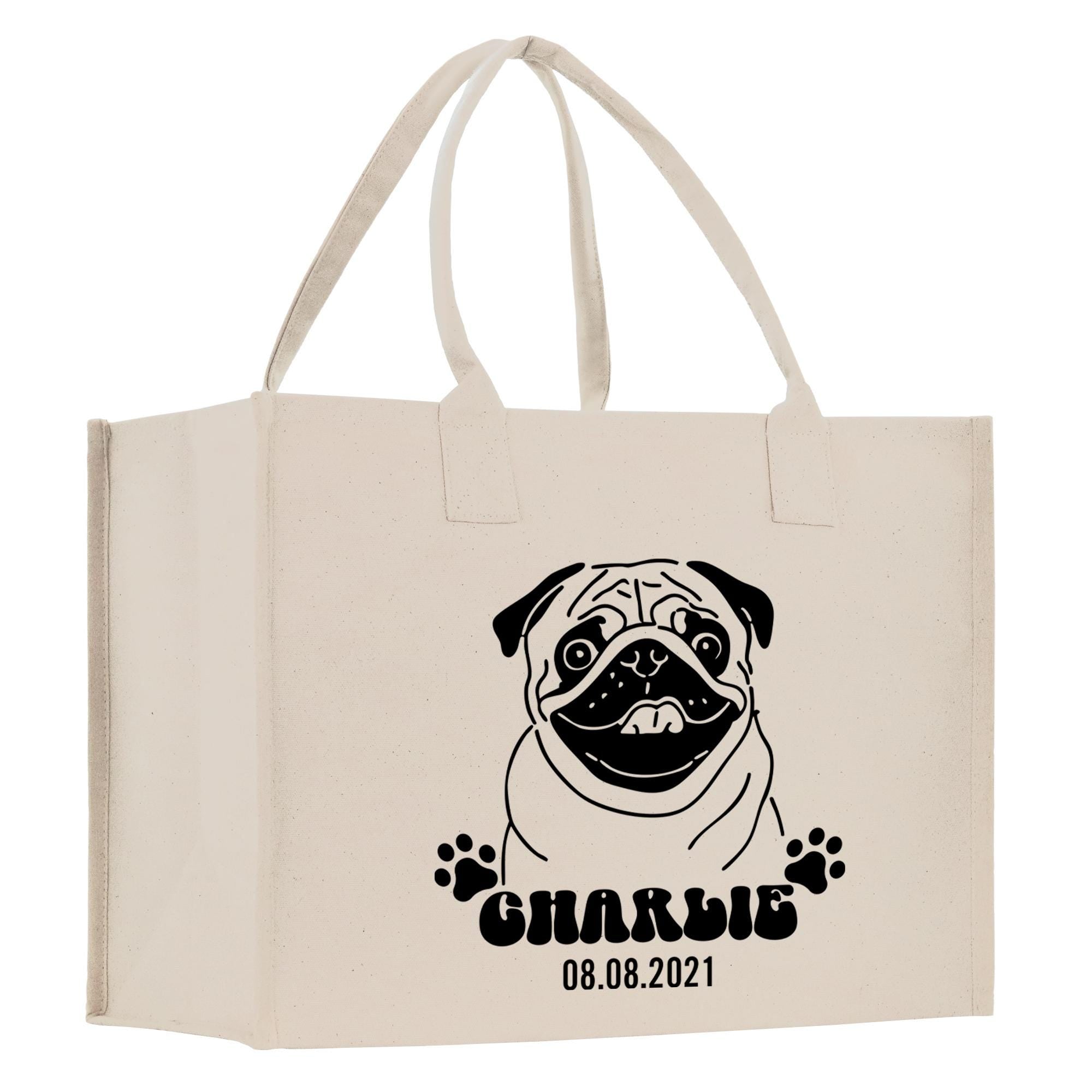 A beige canvas tote bag with a black and white illustration of a pug dog and the text &quot;CHARLIE 08.08.2021&quot; printed on it.