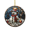 A stained glass ornament depicting a snowman with a red scarf and hat, surrounded by snow and rocks, with two ornaments on its body.