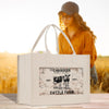 A white tote bag with a vintage-style graphic of a cow and the text "CHANDLER, DETROIT, MICHIGAN, EST. 1950 CATTLE FARM" printed on it, placed on a wooden surface.