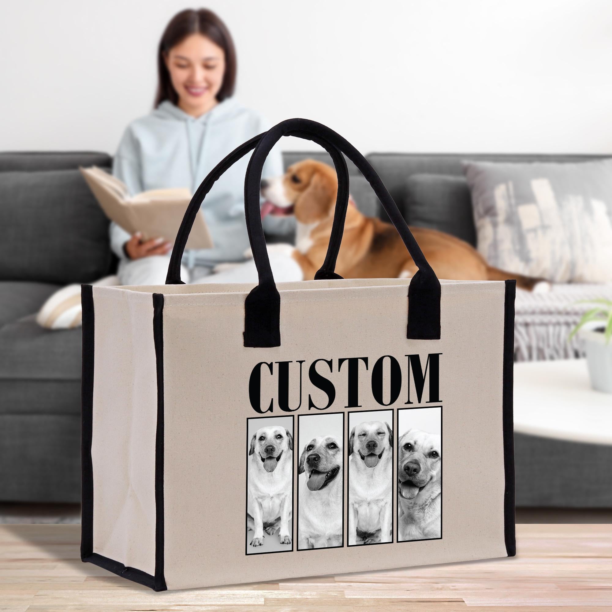 A woman is sitting on a couch, reading a book, while a dog is in the background. A large tote bag with a custom dog image printed on it is placed in front of the woman.