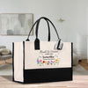A large tote bag with a floral design and text printed on it, placed on a wooden surface.