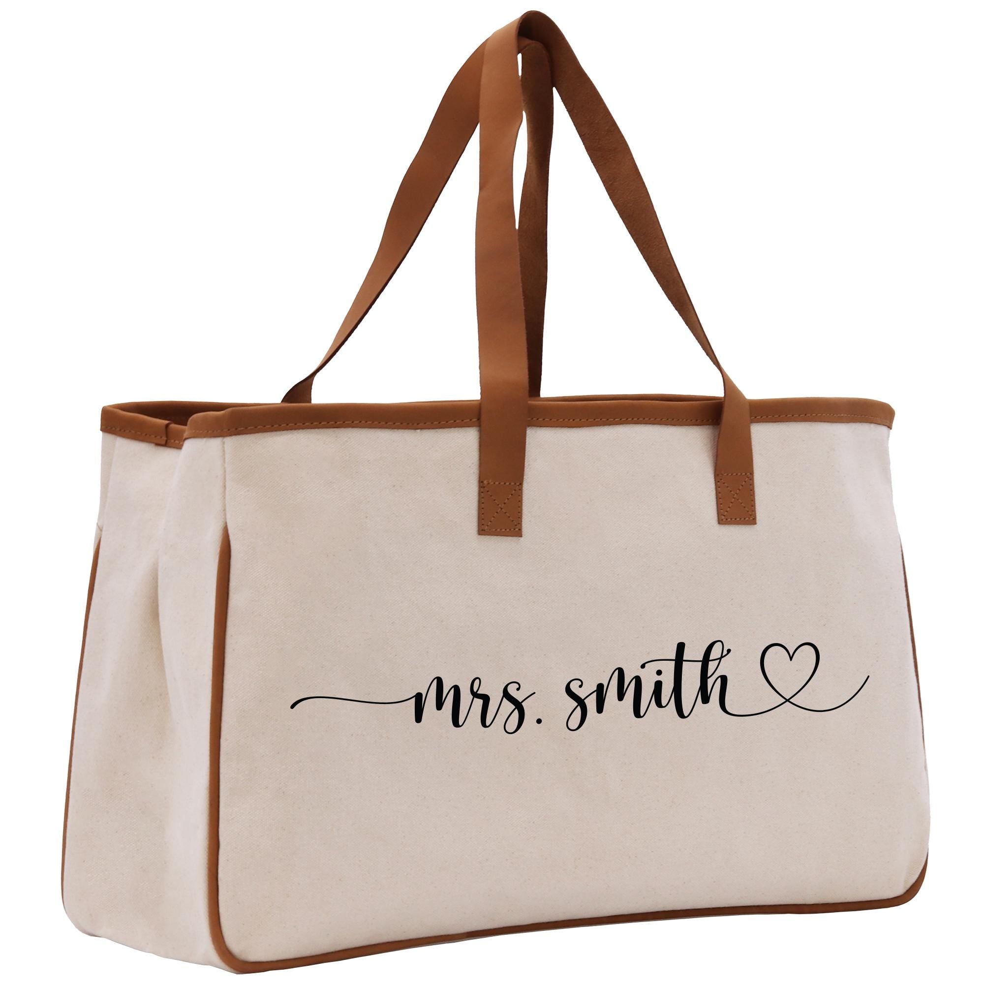 a white canvas bag with a brown leather handle