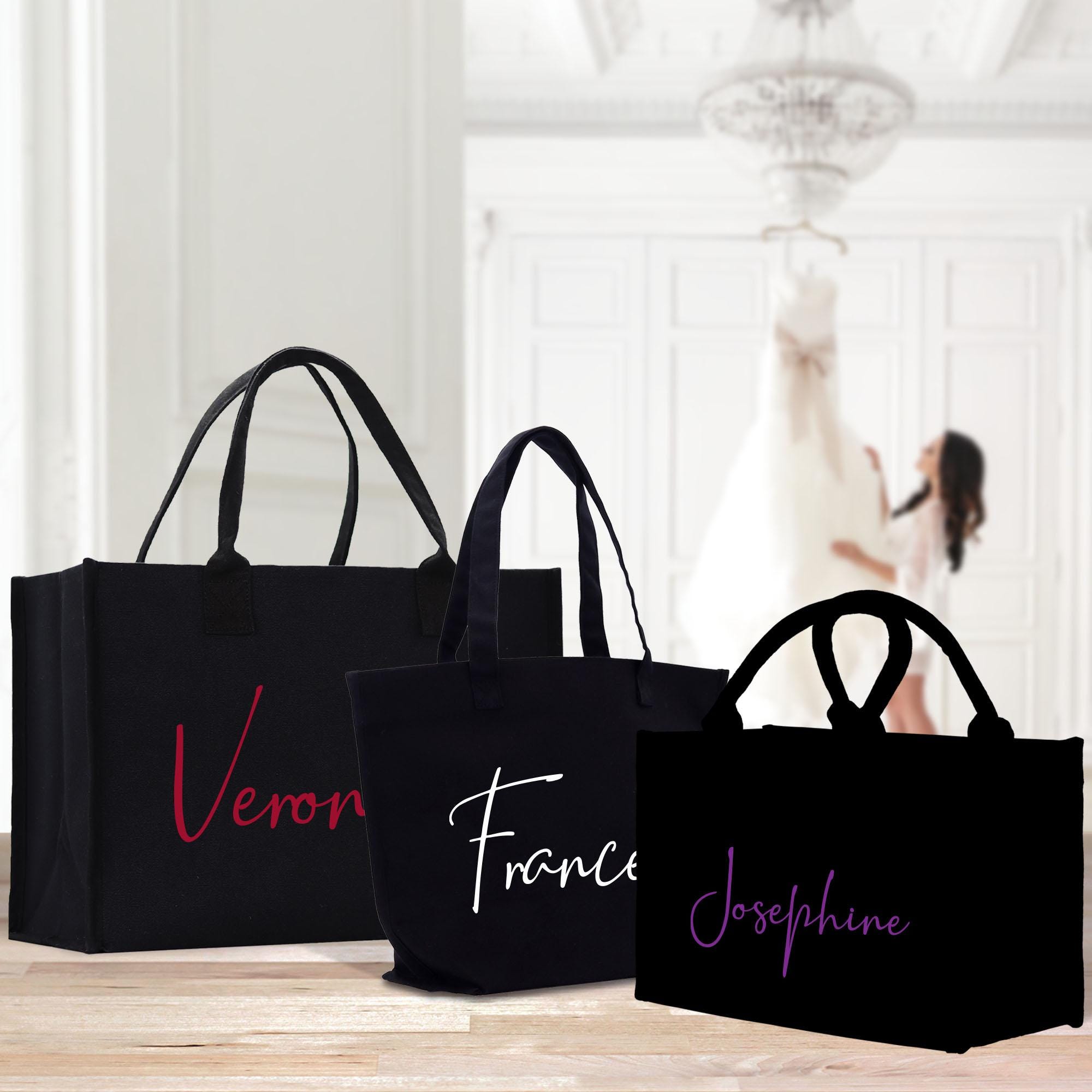 three black shopping bags sitting on top of a wooden table