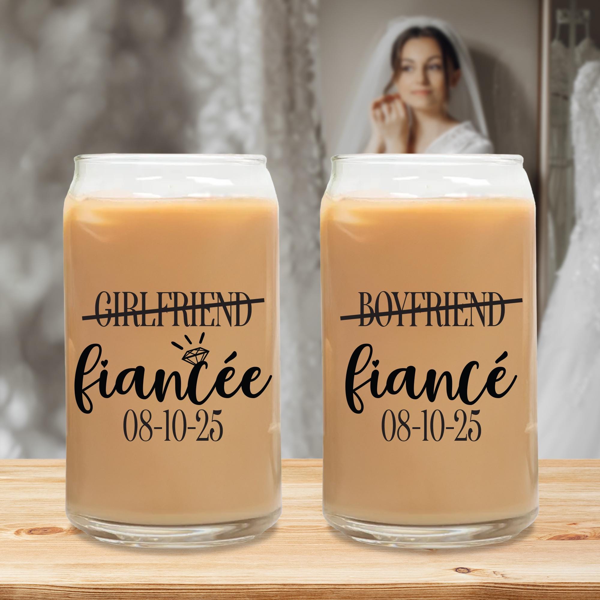 Two glass tumblers with text that reads &quot;GIRLFRIEND fiancee 08-10-25&quot; and &quot;BOYFRIEND fiancee 08-10-25&quot; printed on them, placed on a wooden surface.