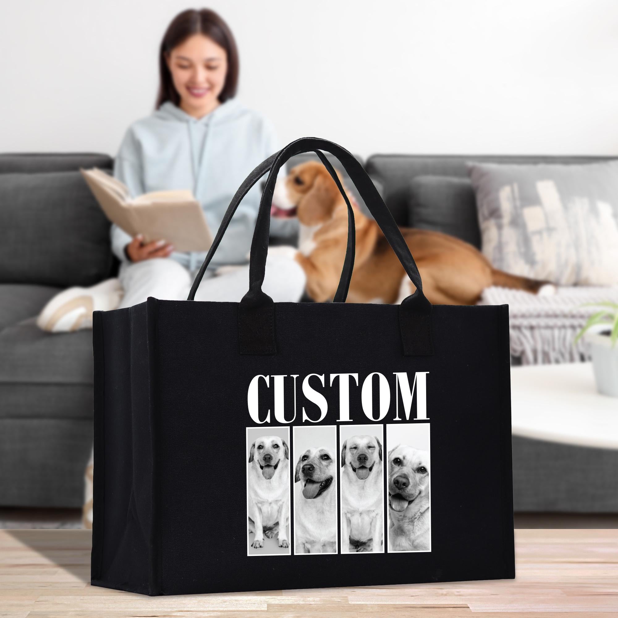 A woman is sitting on a couch, reading a book, while a dog is in the background. A black bag with a custom design featuring four dog portraits is placed in front of the woman.