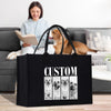 A woman is sitting on a couch, reading a book, while a dog is in the background. A black bag with a custom design featuring four dog portraits is placed in front of the woman.