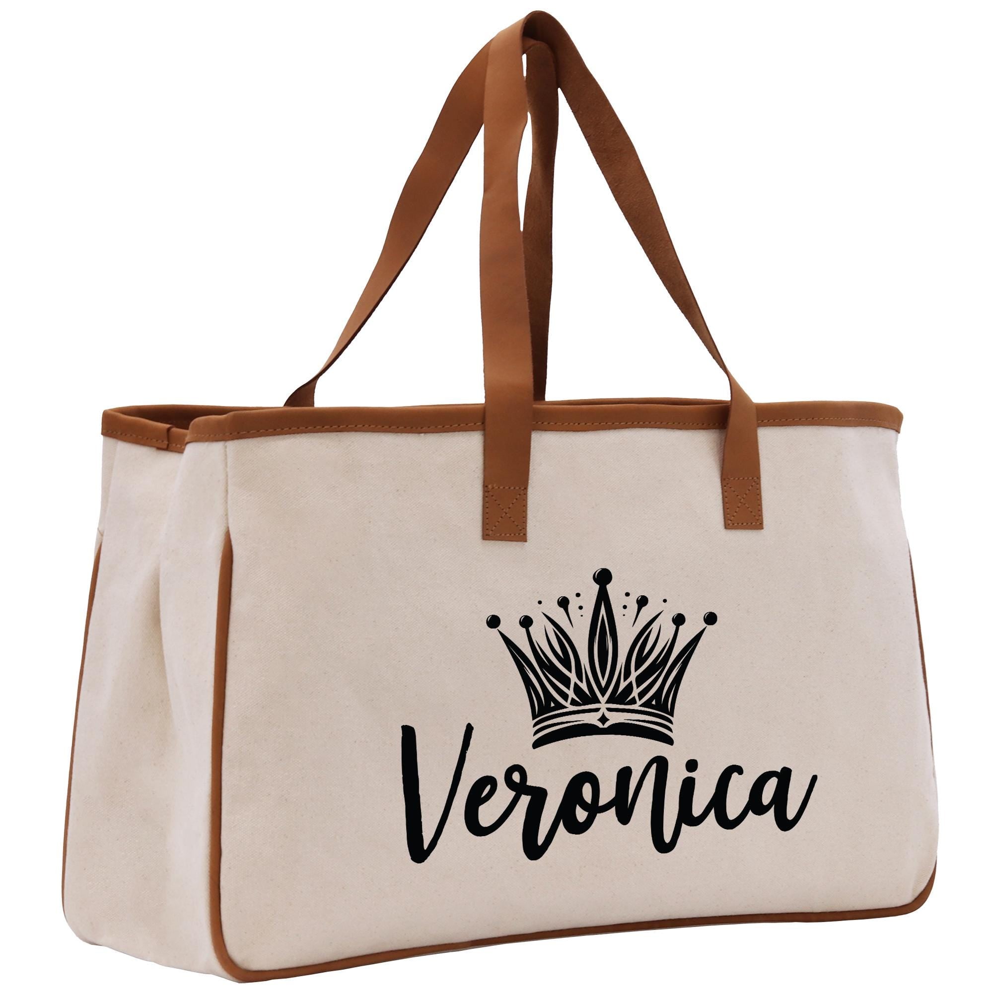 A beige tote bag with a brown handle and a black crown design printed on it.