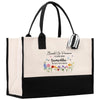 A beige tote bag with a black handle and a black and white striped ribbon attached to it. The bag has a floral design on the front and text that reads "Eccedora Se Preservar - CLASS 2015 - SAMANTHA - DO MAY VIDA MORJOR".