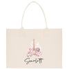 A beige tote bag with a printed image of the Eiffel Tower and pink flowers.