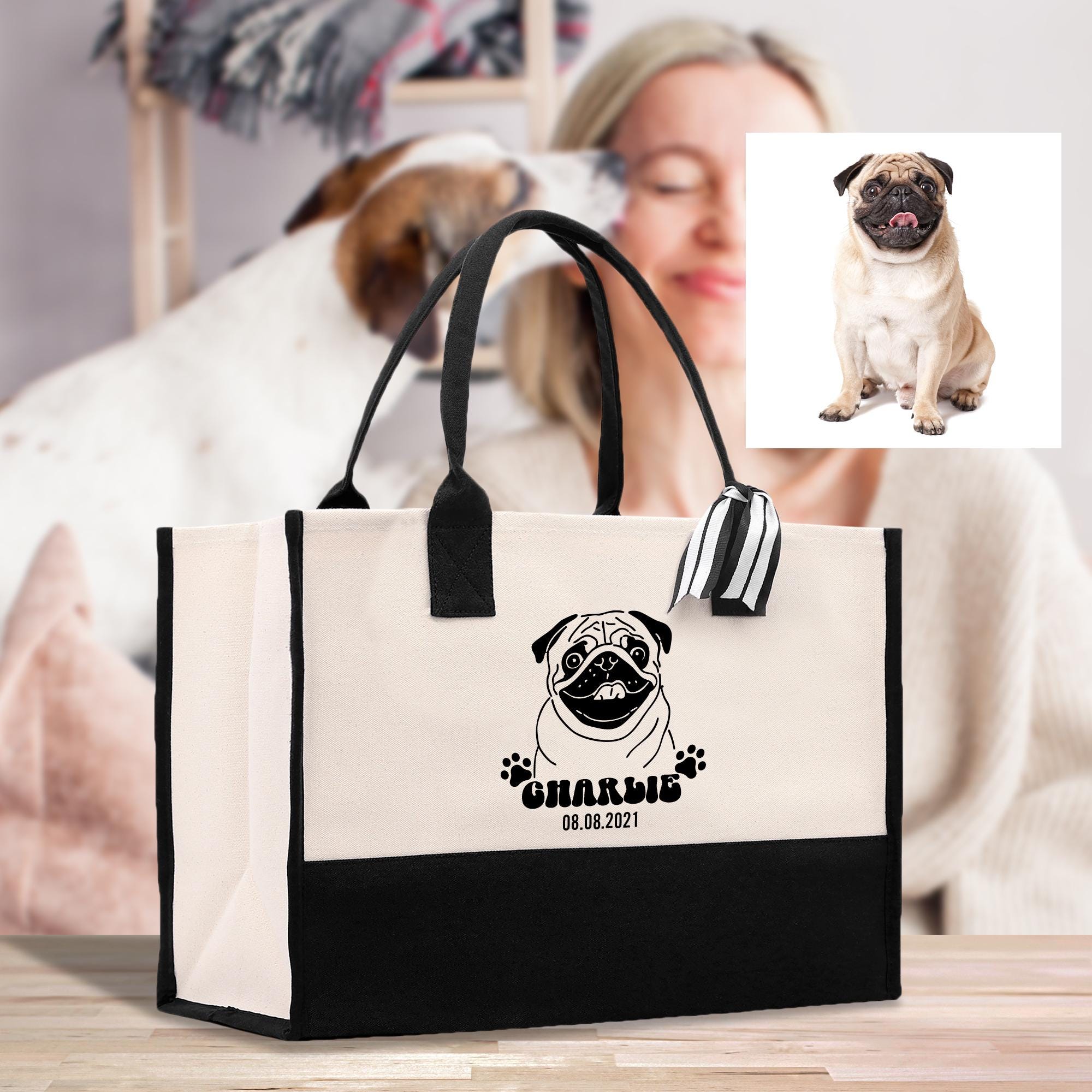 A large tote bag with a pug dog printed on it, featuring a personalized name tag. In the background, there is a woman sitting on a couch, and a photograph of a pug dog is displayed.