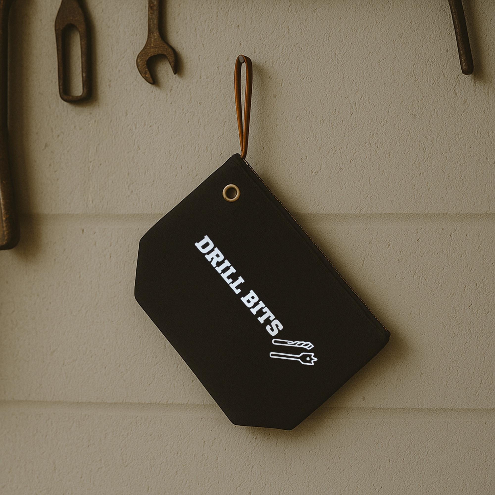 A black tag with white text hanging on a wall, displaying the word &quot;DRILL BITS&quot;.