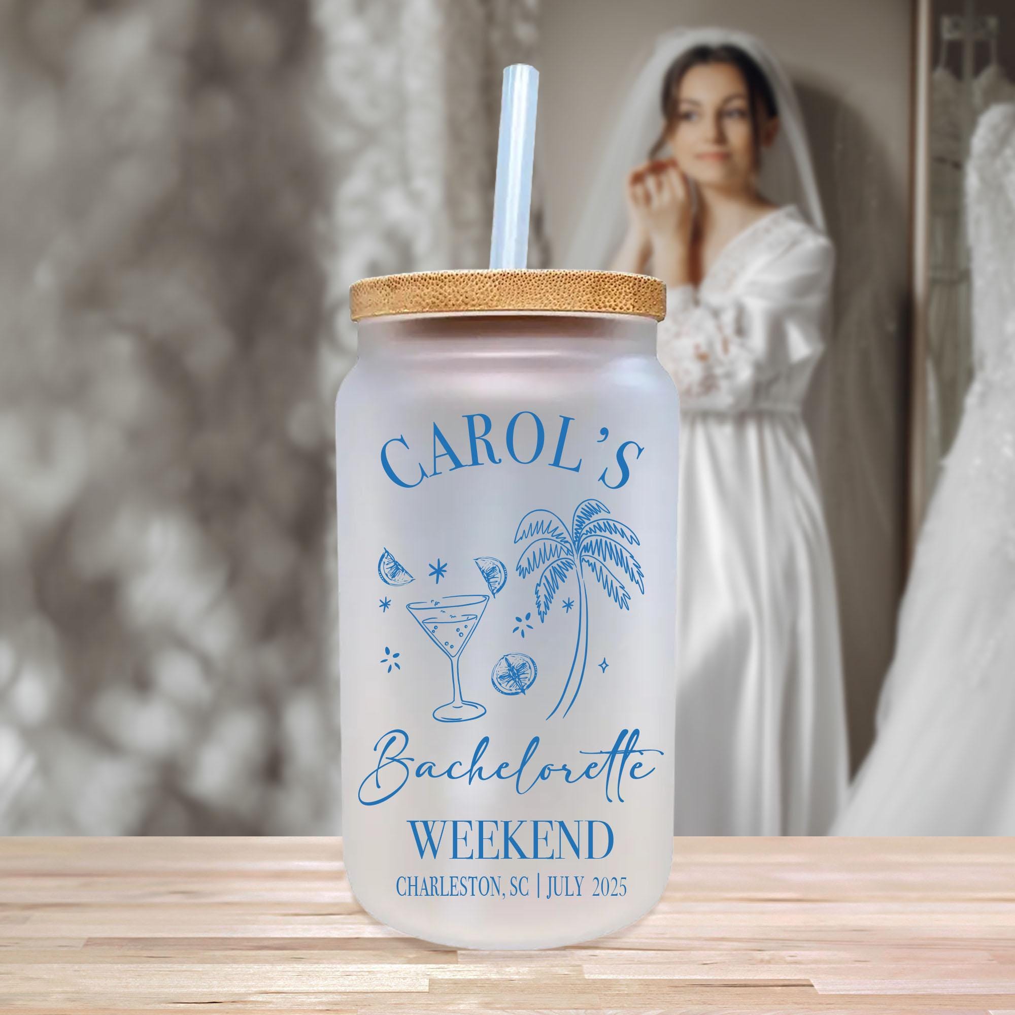 A frosted glass tumbler with a straw, featuring a design of a cocktail glass, palm tree, and star, along with the text &quot;CAROL&#39;S Bachelorette Weekend Charleston, SC July 25, 2015&quot;.