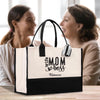 two women sitting at a table with a black and white bag