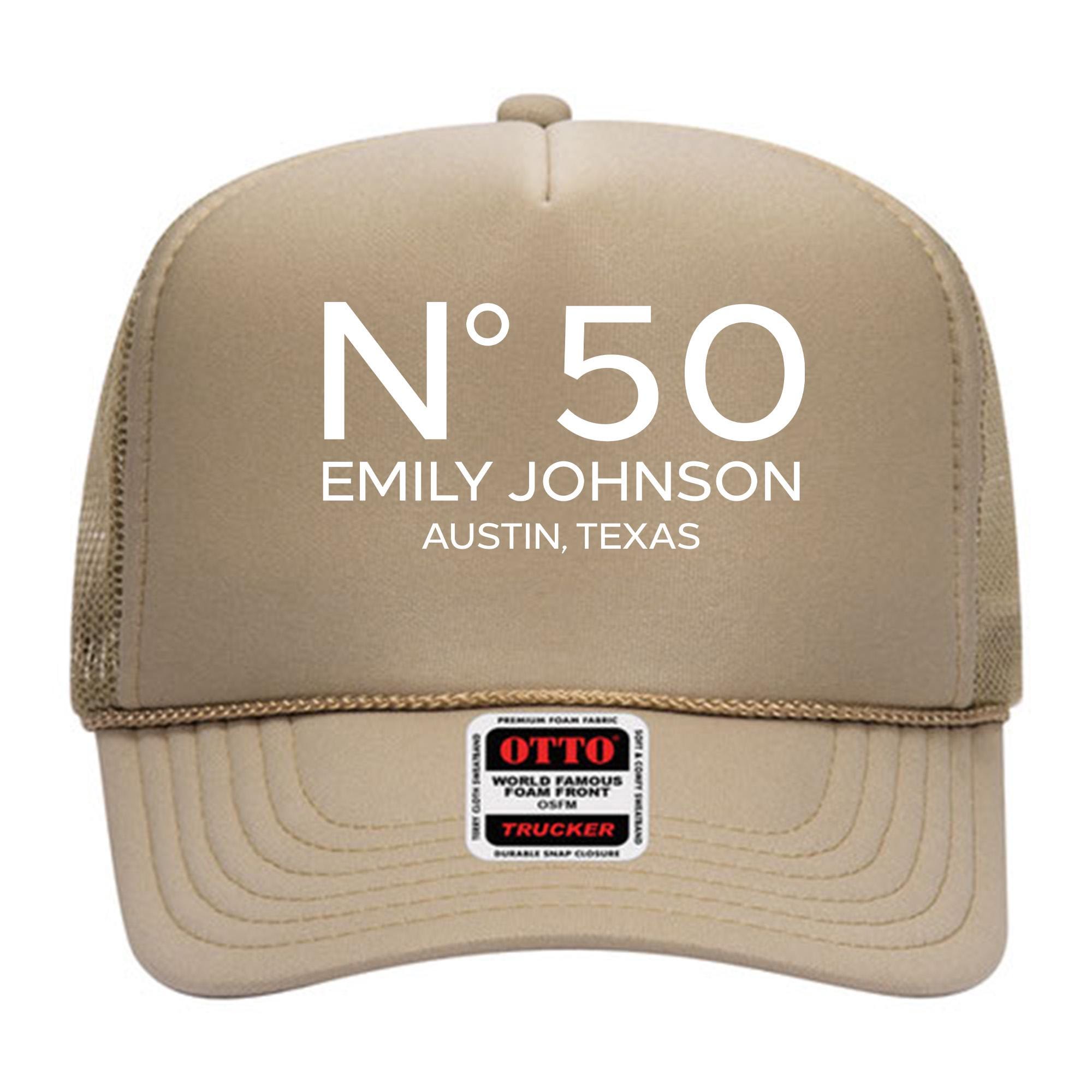 A tan-colored trucker hat with the text &quot;N°50 EMILY JOHNSON AUSTIN, TEXAS&quot; printed on it.