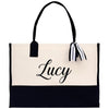 A black and white tote bag with the name "Lucy" printed on it in a cursive font.