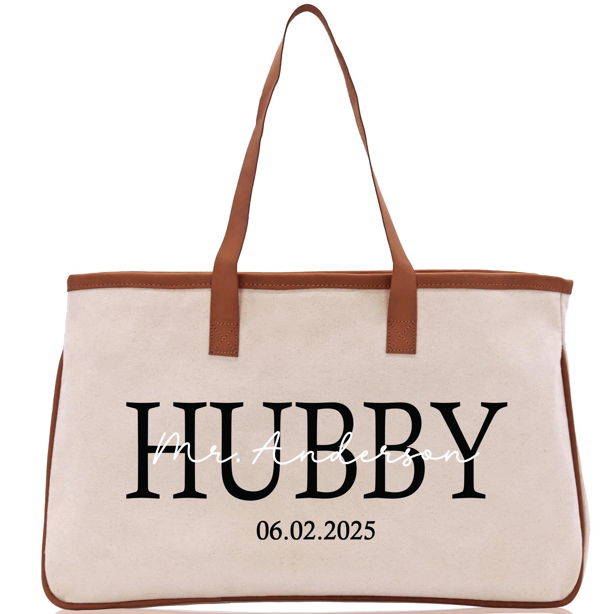 a white canvas bag with a brown leather handle