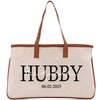 a white canvas bag with a brown leather handle