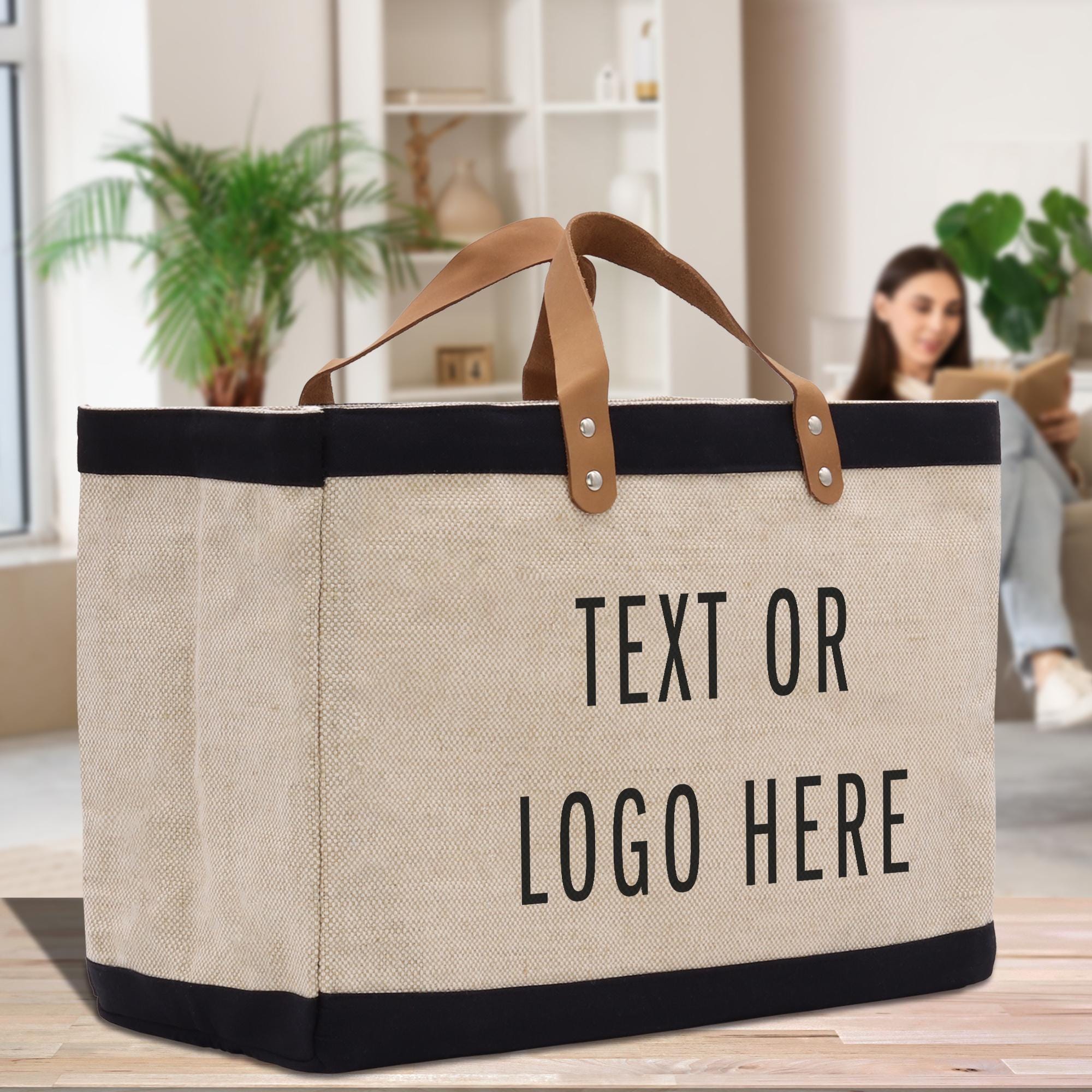 A large beige tote bag with black trim and brown handles, featuring the text &quot;Text or Logo Here&quot; printed on it.