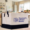 A large tote bag with the text "Thomas' Library Books" printed on it, featuring an illustration of a stack of books.