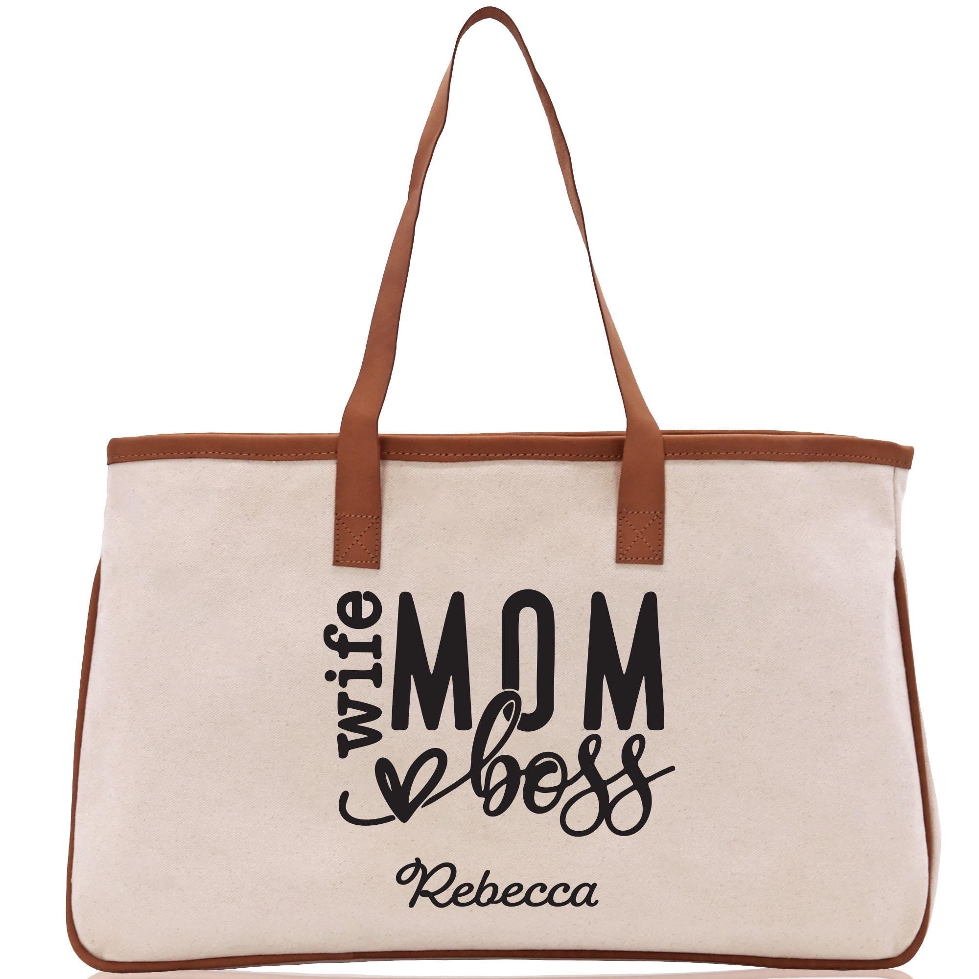 a white canvas bag with a brown leather handle