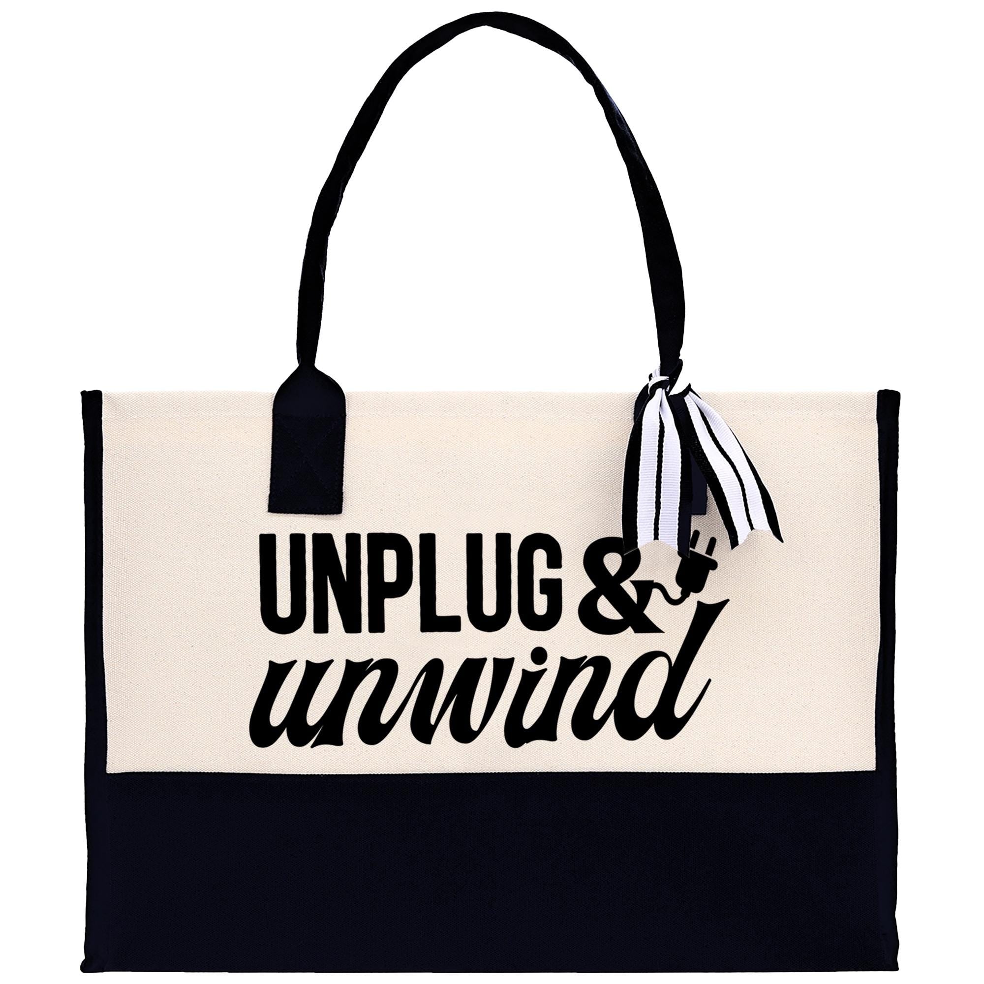 A black and white tote bag with the text "UNPLUG & UNWIND" printed on it.
