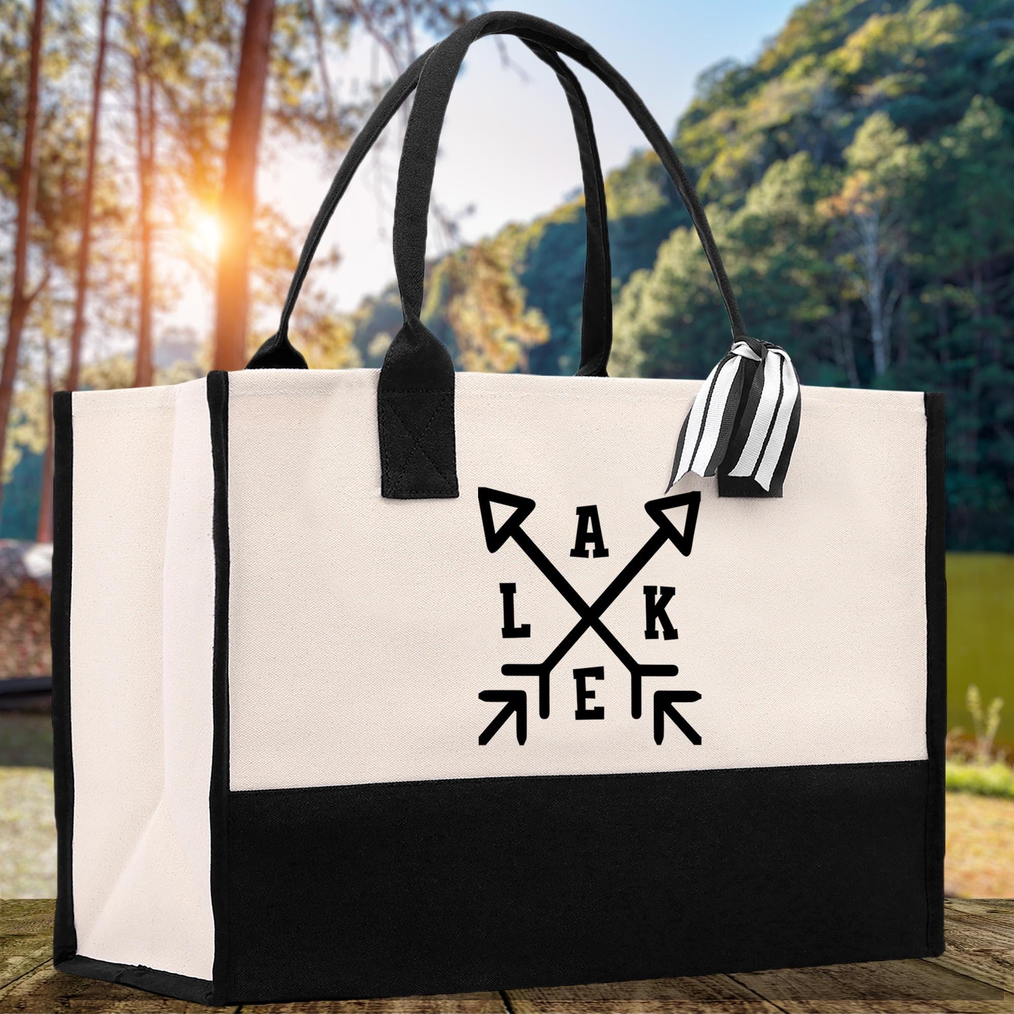 A black and white tote bag with a graphic design on it, placed on a wooden surface with a natural outdoor background.