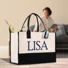 A large tote bag with the name "LISA" printed on it, placed on a wooden floor in a room with a woman sitting on a couch in the background.