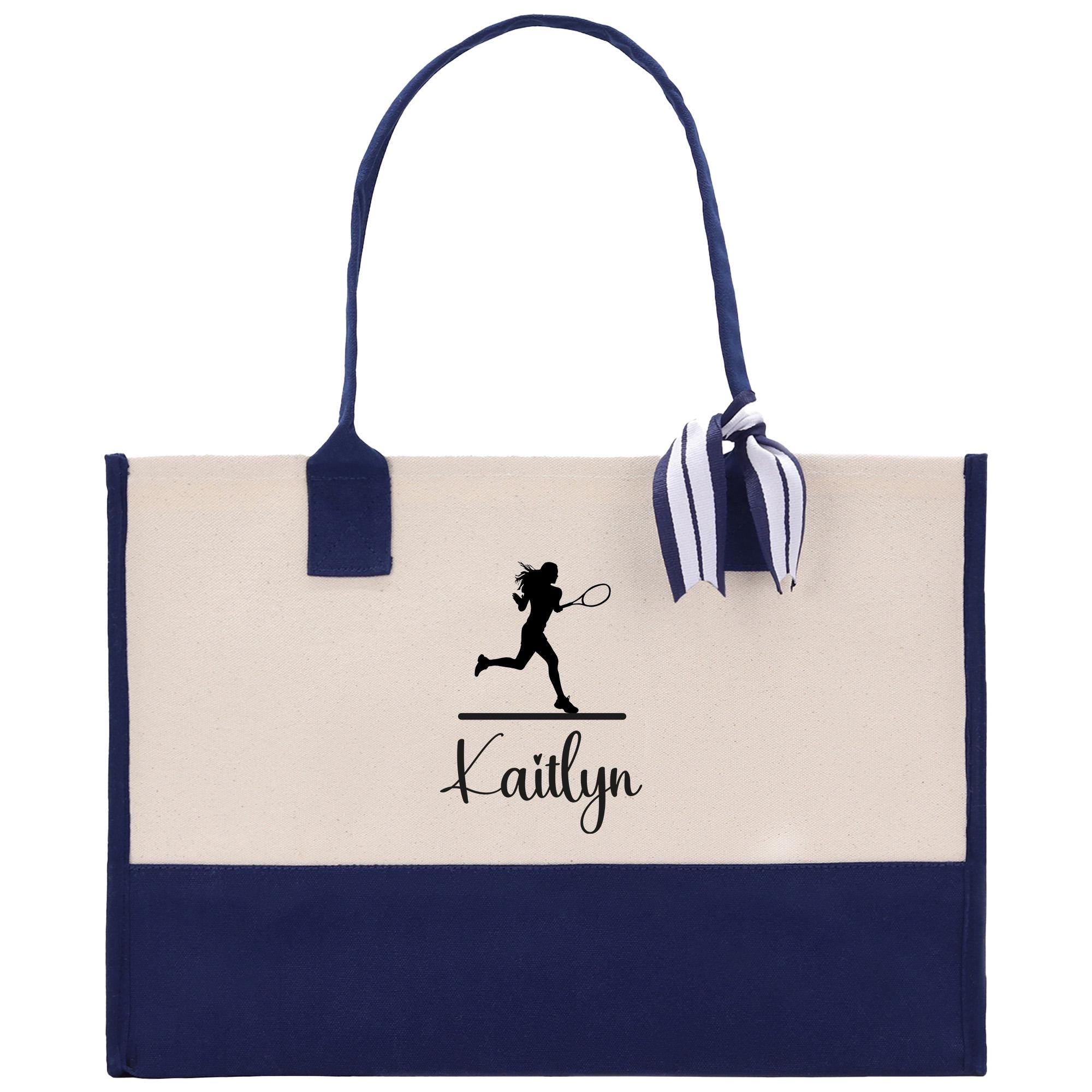 A tote bag with a navy blue trim and a white background. The bag has a tennis player silhouette and the name &quot;Kaitlyn&quot; printed on it.