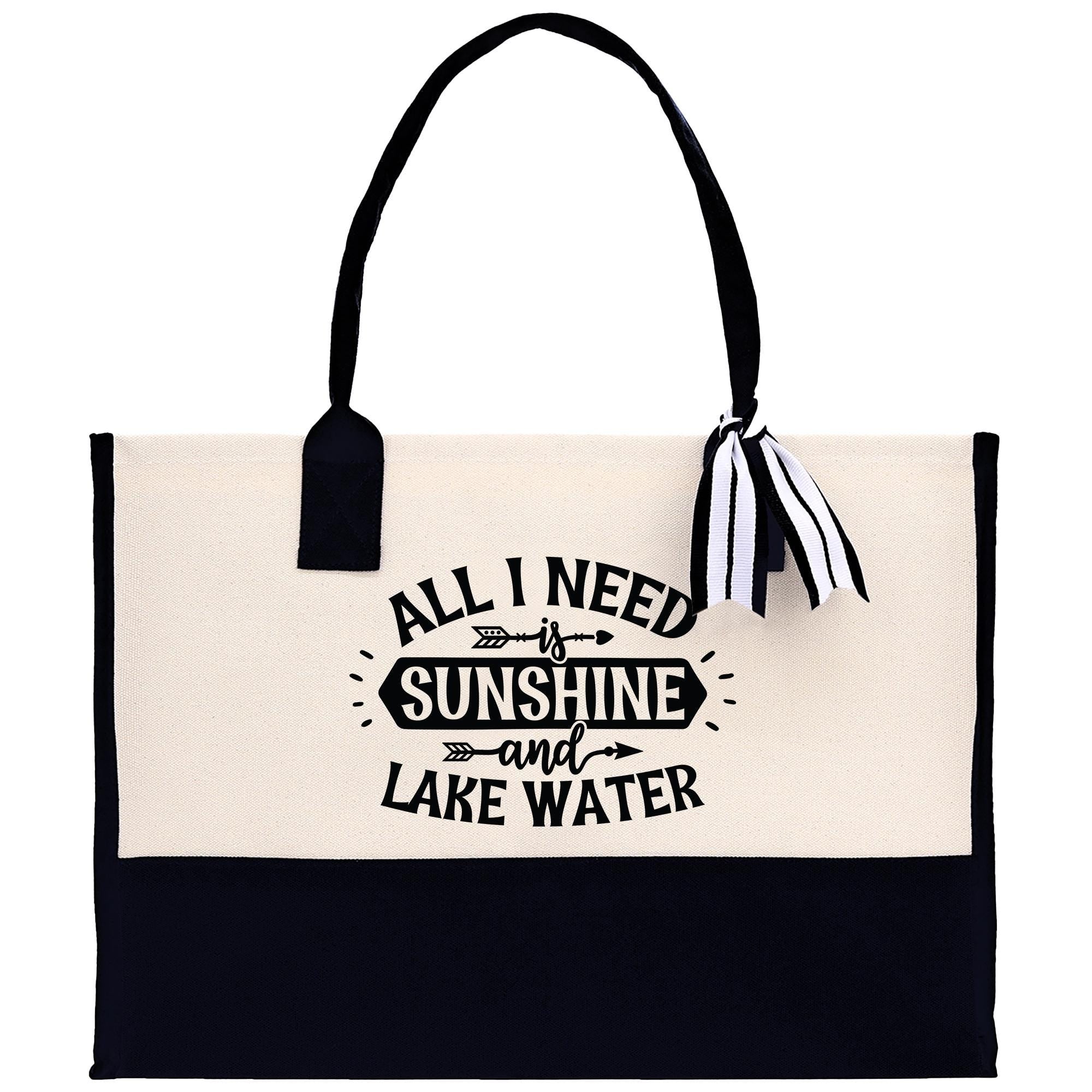 A tote bag with a black and white design, featuring the text "All I need is sunshine and lake water" printed on it.