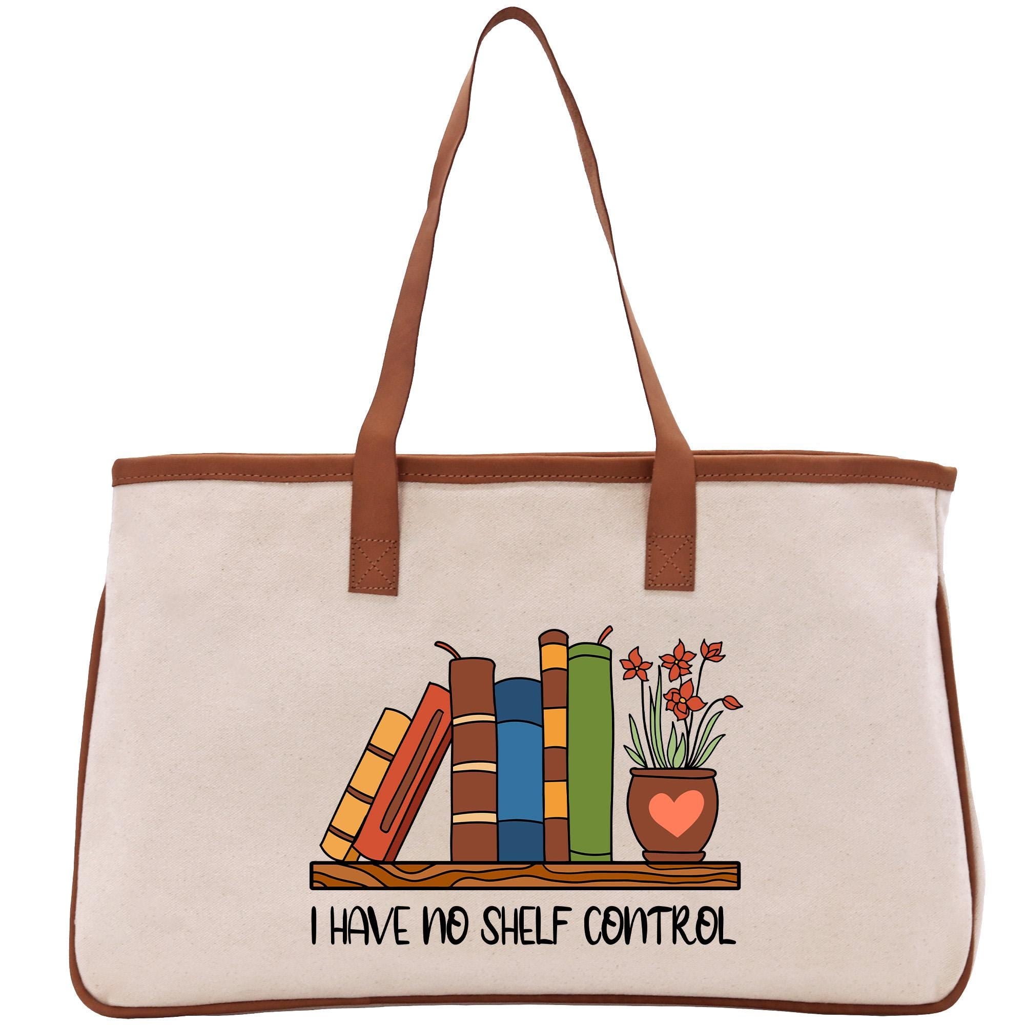 A beige tote bag with a printed design on it, depicting a bookshelf with colorful books and a potted plant. The text below the design reads &quot;I HAVE NO SHELF CONTROL&quot;.