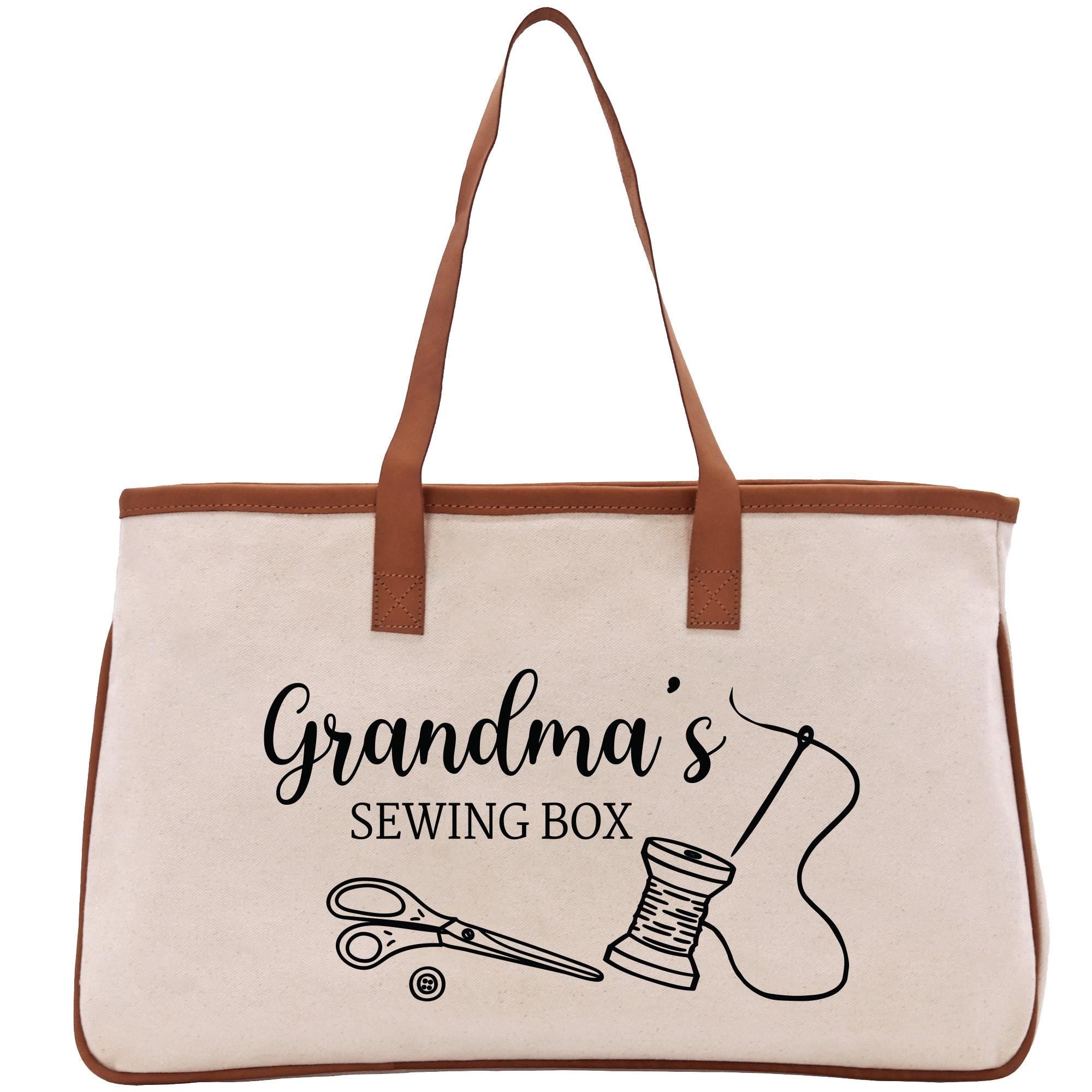 A beige tote bag with a brown handle and a printed design that says &quot;Grandma&#39;s Sewing Box&quot; along with illustrations of sewing tools.