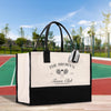 A large tote bag with a tennis club logo printed on it, placed on a wooden surface against a backdrop of a tennis court and trees.