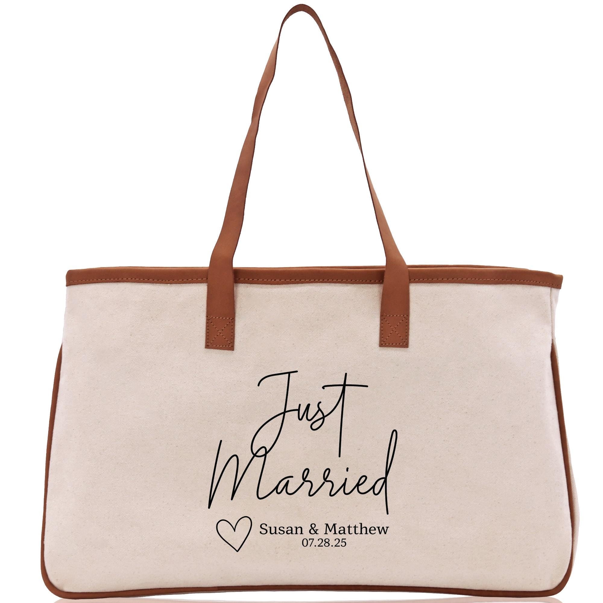 A tan tote bag with a brown leather strap and the text &quot;Just Married Susan & Matthew 07:28:25&quot; printed on it.