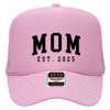A pink baseball cap with the text "MOM EST. 2025" printed on it.