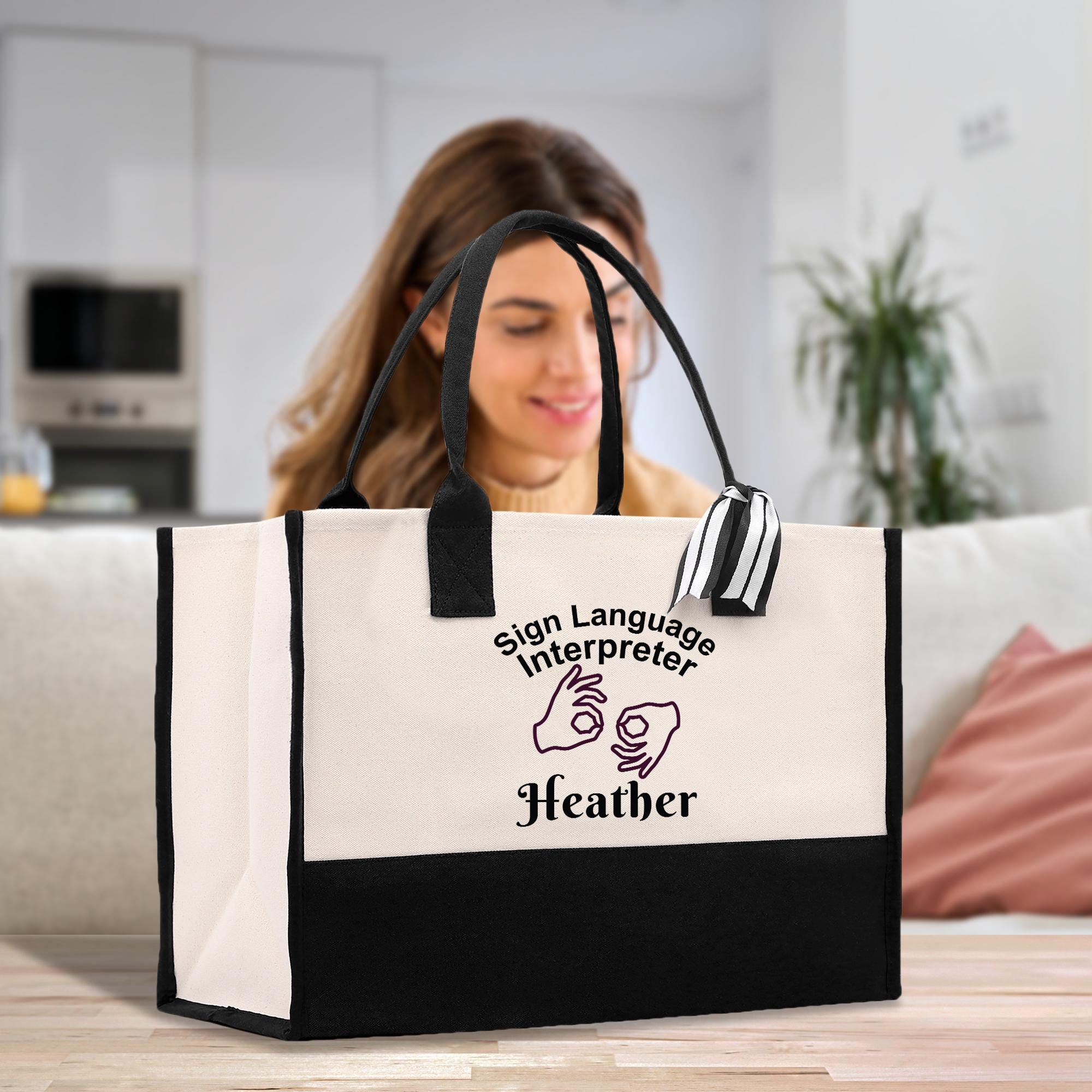 A woman is sitting on a couch in a living room, looking at a large tote bag with a sign language interpreter printed on it.