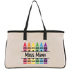 A beige canvas tote bag with a black handle and straps, featuring a colorful design of crayons arranged in a row and the text "Miss Magi" printed on it.