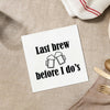 a white napkin with a humorous text printed on it, placed on a table with various tableware items such as a fork, knife, and spoon.