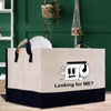 A beige and black storage bin with a cartoon image of a toilet paper roll and the text "Looking for ME?" printed on it.