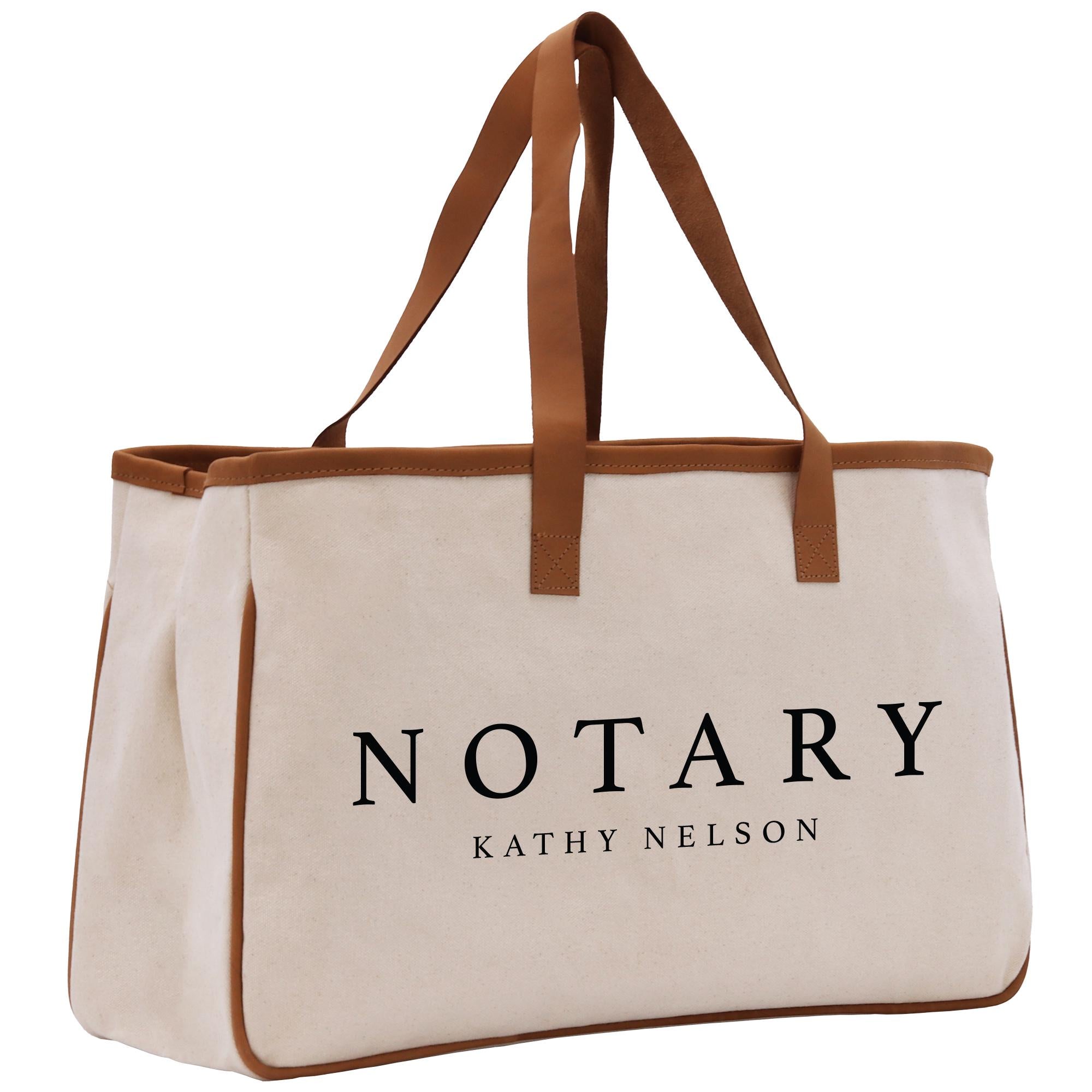 A beige canvas tote bag with brown straps and the word &quot;NOTARY&quot; printed on it.