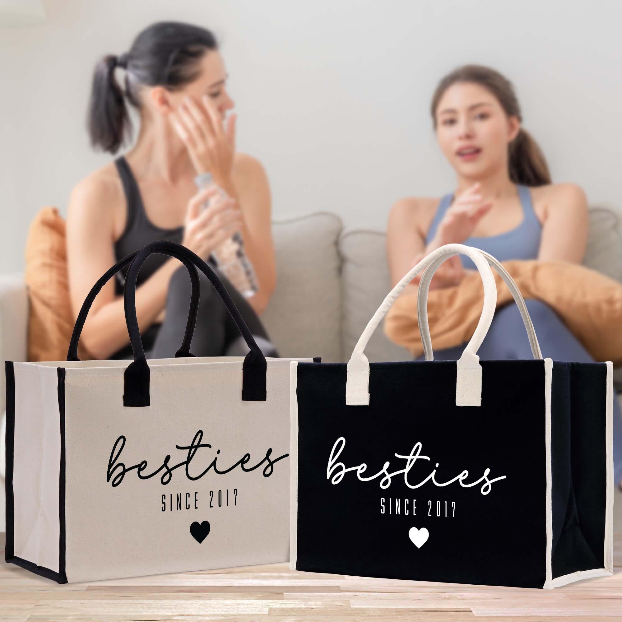 Two women sitting on a couch, one holding a remote control, with two handbags in the foreground.