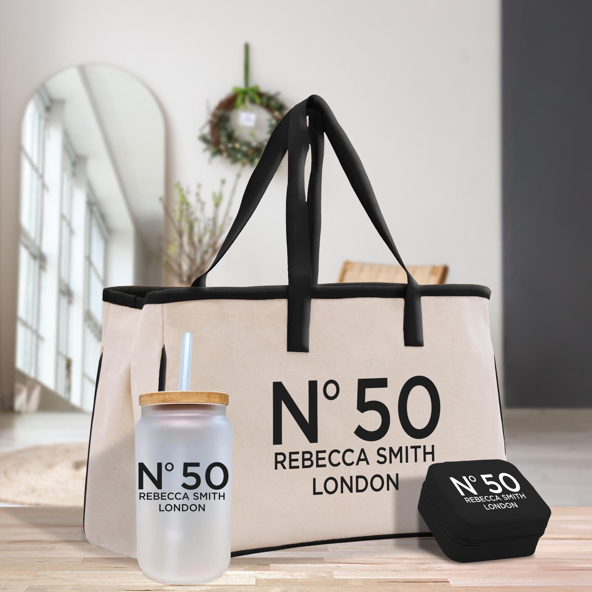 A beige tote bag with the text &quot;N°50 Rebecca Smith London&quot; printed on it, along with a matching straw cup and a small black box with the same text.