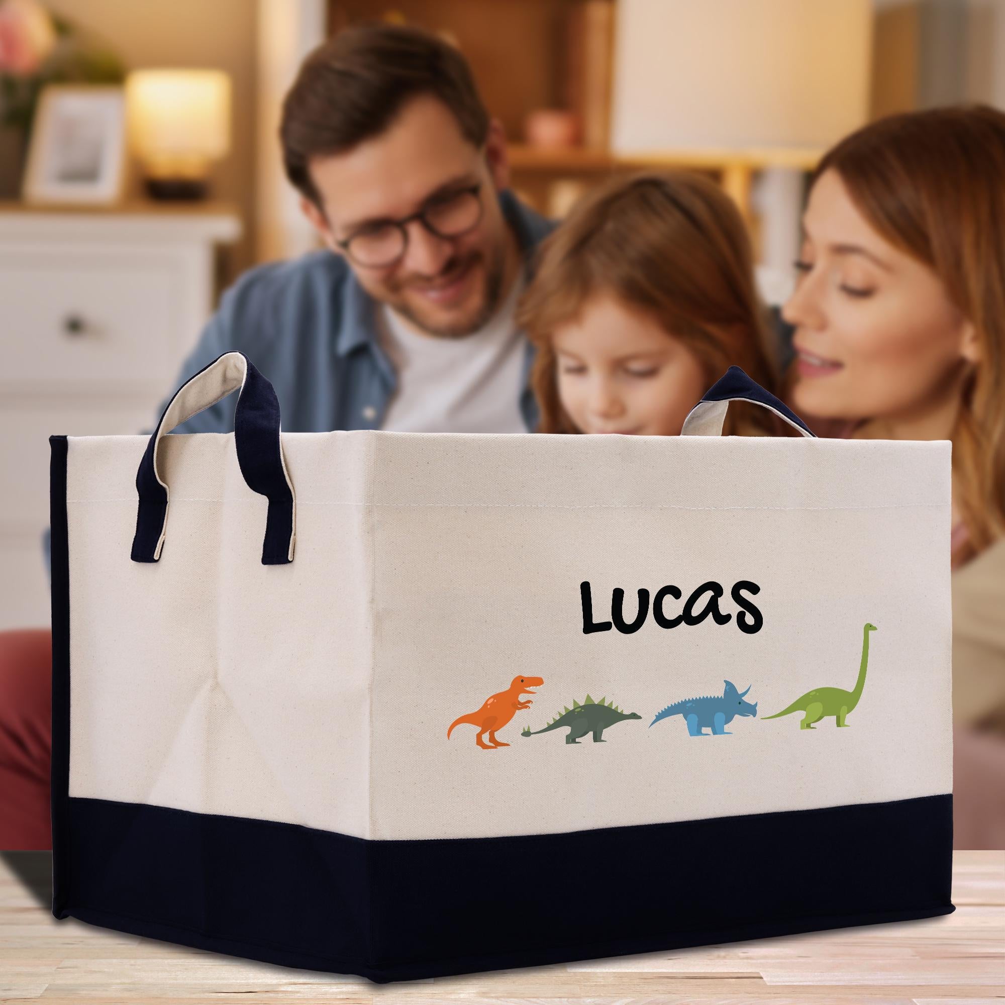 A family of three, including a man, a woman, and a young girl, are gathered around a large white tote bag with dinosaur illustrations and the name &quot;Lucas&quot; printed on it.