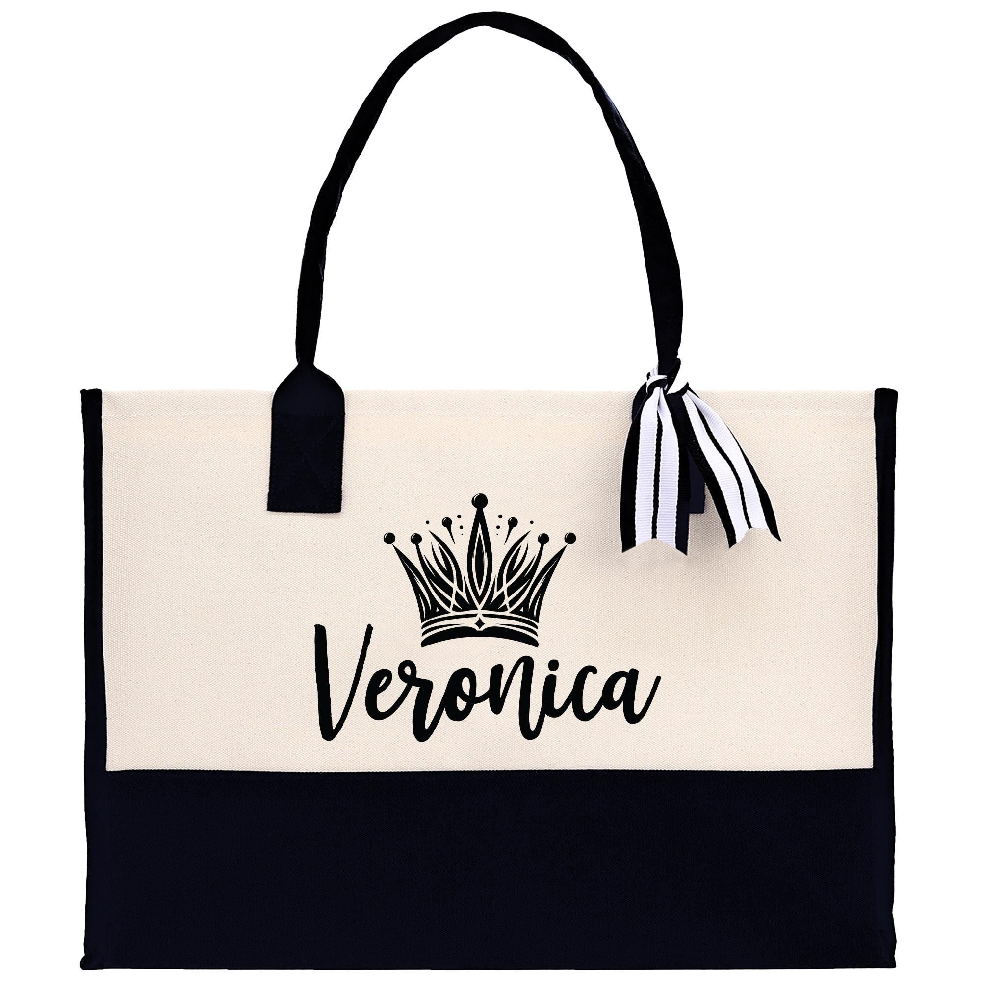 A beige tote bag with a black handle and a black and white striped ribbon tied around it. The bag has a crown design on the front and the name &quot;Veronica&quot; printed on it.