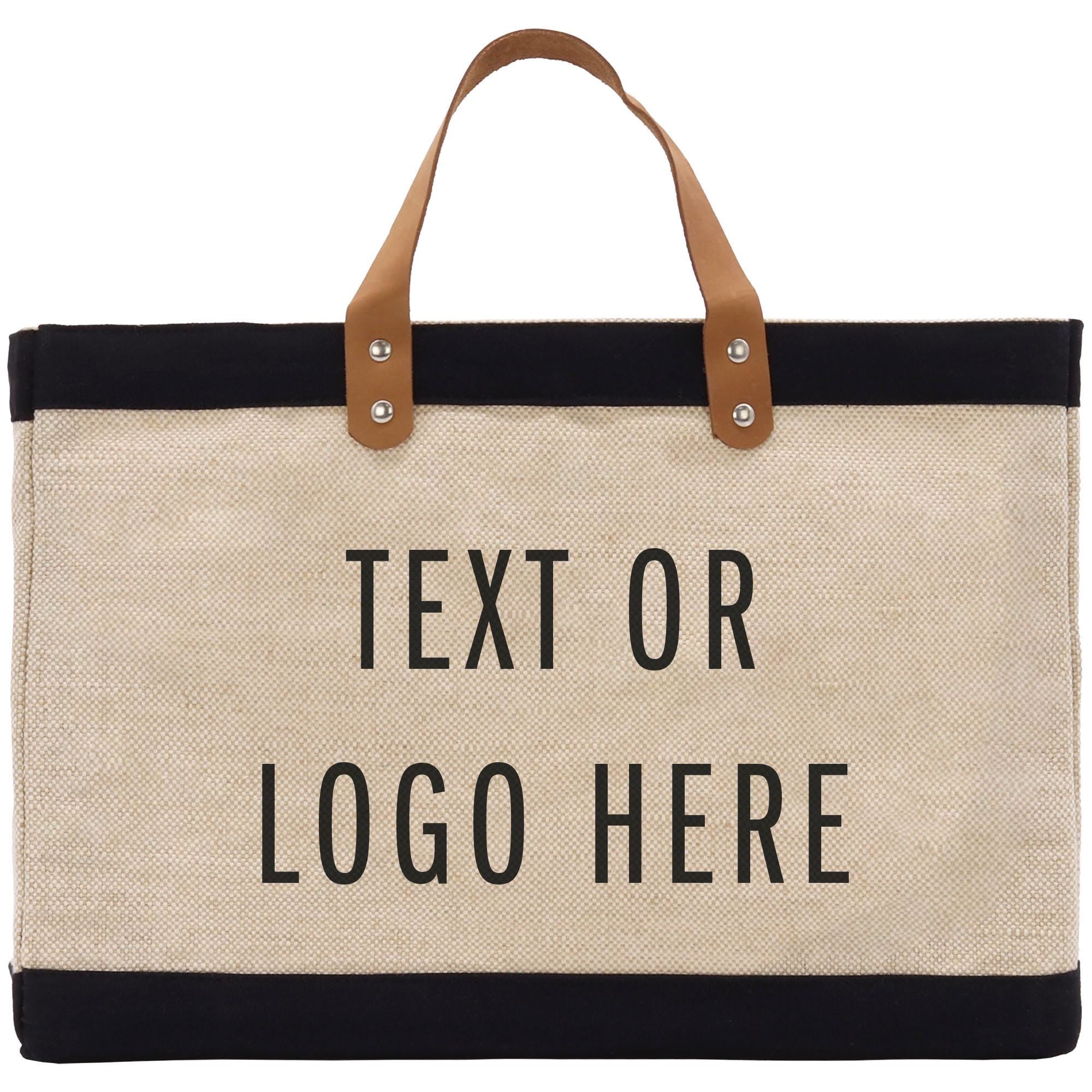 A beige tote bag with black trim and leather handles, featuring the text &quot;Text or Logo Here&quot; printed on it.
