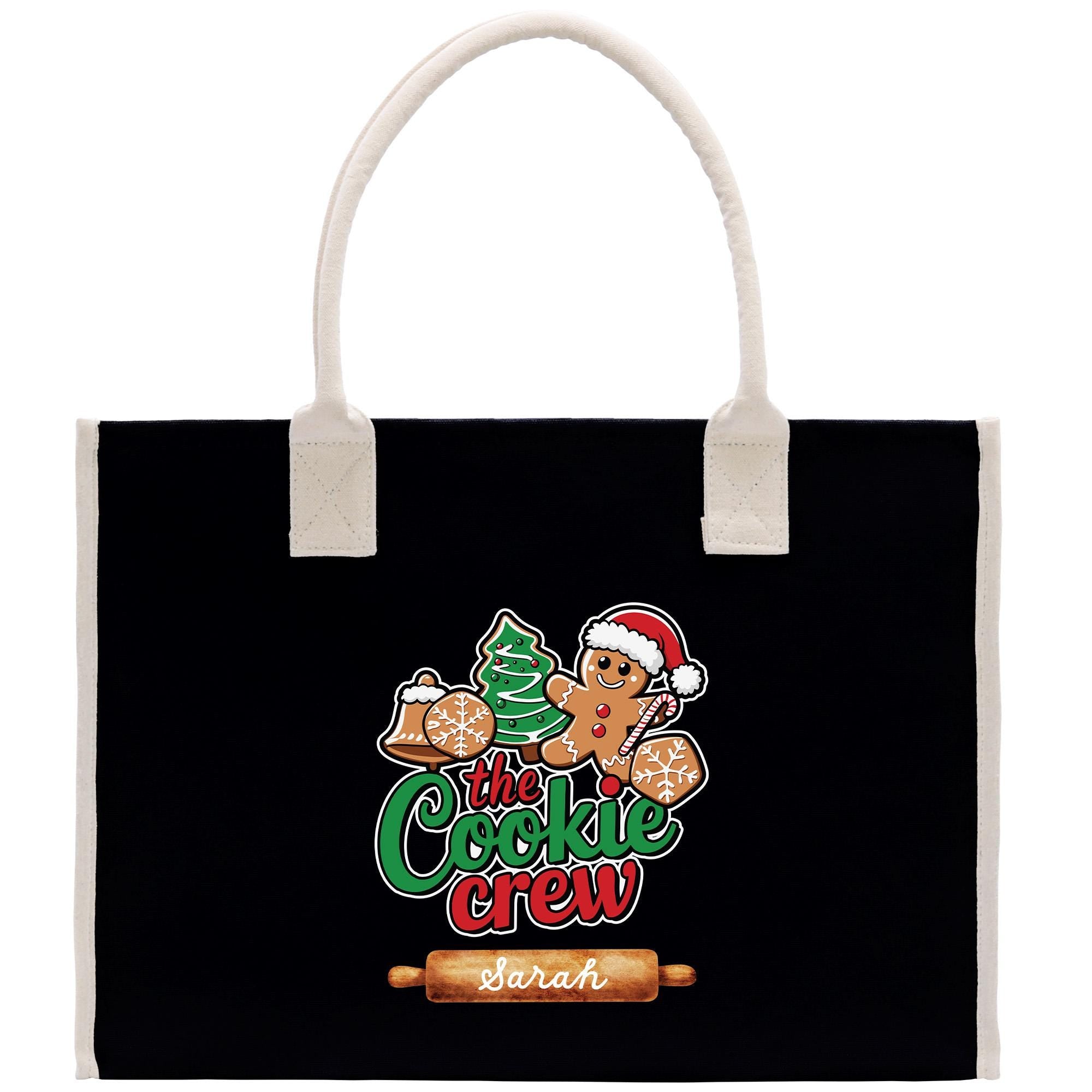 A black tote bag with a white handle and a graphic design featuring a gingerbread man, a Christmas tree, and the text &quot;The Cookie Crew&quot; and &quot;Sarah&quot;.