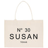 A beige tote bag with the text "N° 30 SUSAN TEXAS" printed on it.