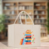 A white tote bag with a colorful graphic design depicting a stack of books and a cat on top.