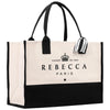 A large tote bag with a black and white color scheme, featuring the text "FONDÉ EN 1954" and "REBECCA PARIS" printed on it.